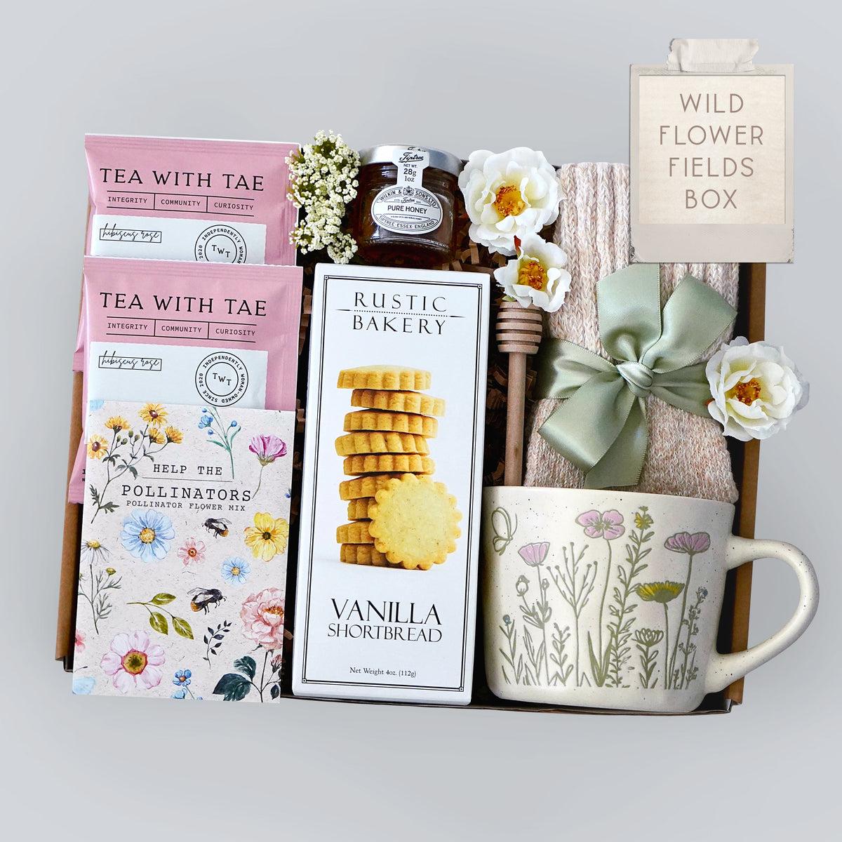 Gift box with tea, cookies, and a mug on a light gray background