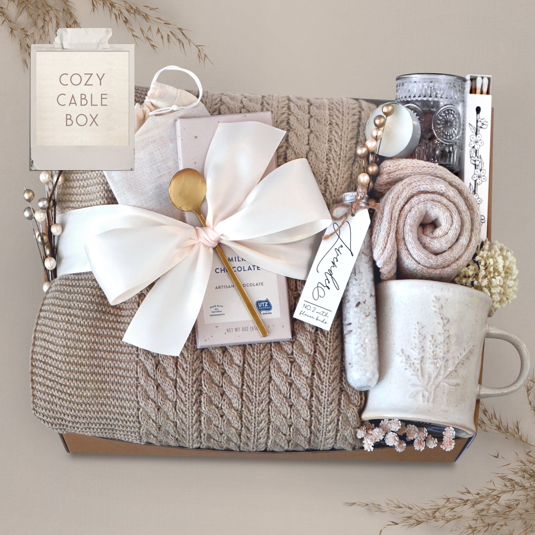 Wildflower Pop Cozy Cable Blanket Gift Box with tan cable knit blanket, Moonstruck Milk Chocolate, Floral bath salts, Lavender Sprig Mug, Cozy Boot socks, Tea, votive and Tea Light 