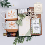 Gift box with mugs, tea, and a chocolate bar with decorative elements on a light background.