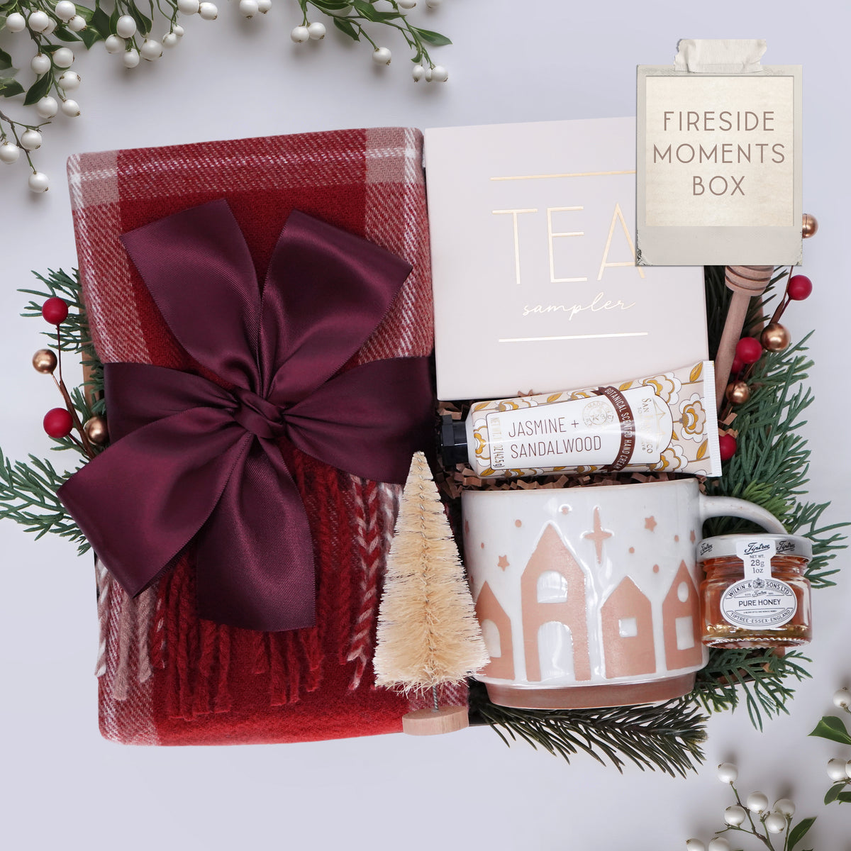 Fireside Moments Box with a mug, tea, and other items on a white background with Christmas decorations.