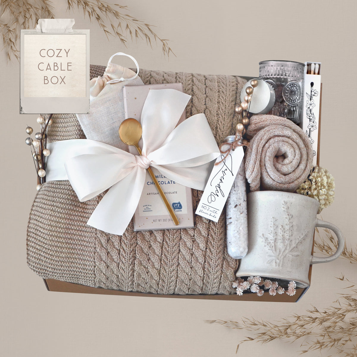 Wildflower Pop Cozy Cable Blanket Gift Box with tan cable knit blanket, Moonstruck Milk Chocolate, Floral bath salts, Lavender Sprig Mug, Cozy Boot socks, Tea, votive and Tea Light