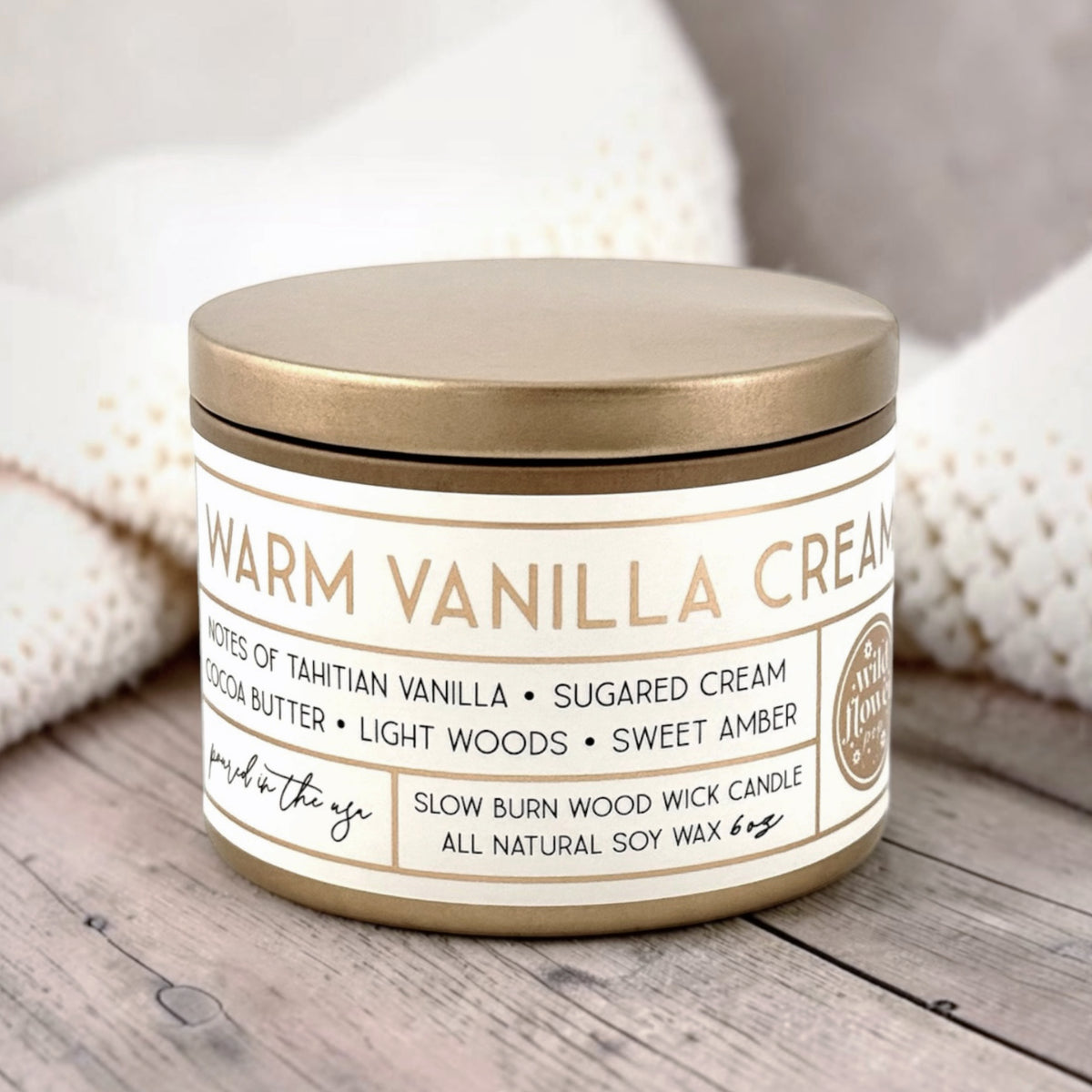 Candle labeled 'Warm Vanilla Cream' on a wooden surface with soft background