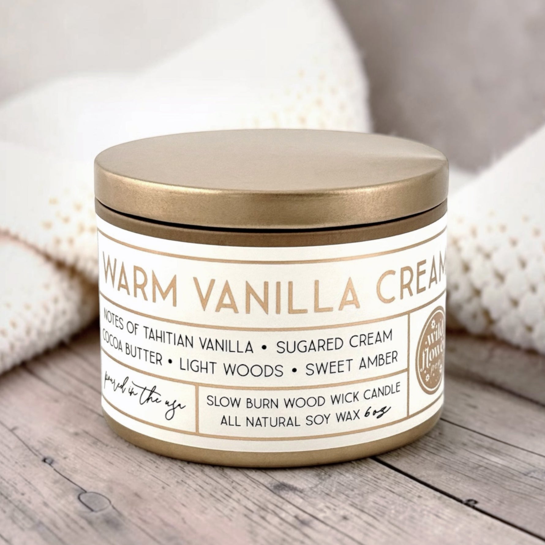 Candle labeled 'Warm Vanilla Cream' on a wooden surface with soft background